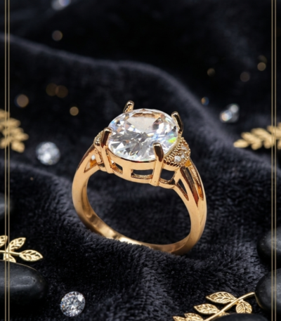 Clear oval statement ring with gold-tone setting and sparkling pavé-style shoulder accents by https://vastorastore.com/