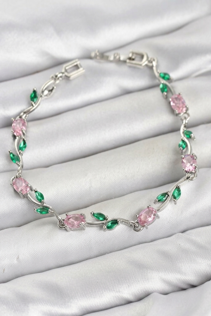 Tulip Bracelet – Pink and Green Floral Jewellery Tulip Bracelet with pink oval stones, green leaf-shaped accents, and a silver-tone floral design on white satin.