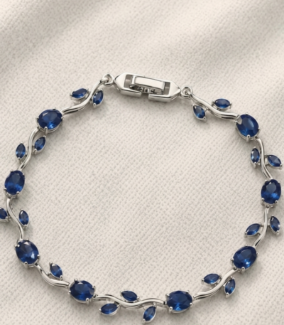 Tulip Bracelet with deep blue oval stones, leaf-shaped accents, and silver-tone detailing on cream fabric.